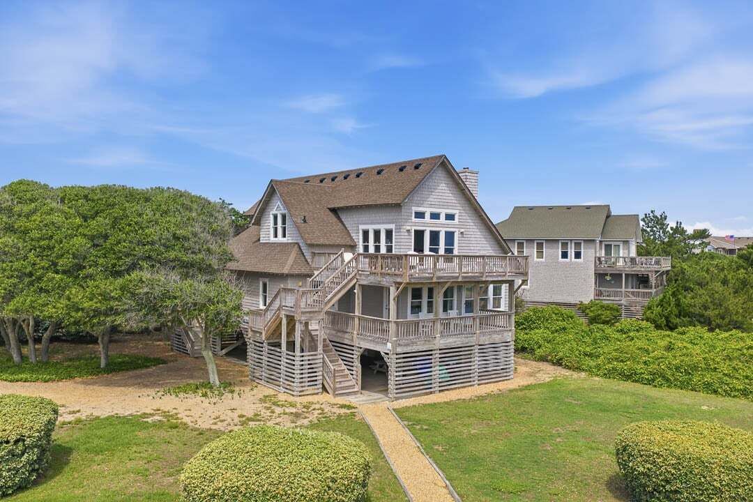 A two-story house with a balcony, a covered porch, and a driveway leading to the entrance.