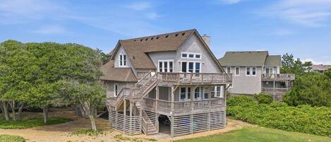 A two-story house with a balcony, a covered porch, and a driveway leading to the entrance.