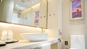 Ein modernes Badezimmer mit einem großen, weißen Waschbecken, einem Spiegel und einer Toilette.