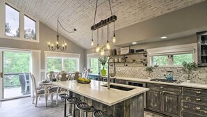 Una cocina amplia con una isla grande, armarios de madera y un comedor con sillas blancas.