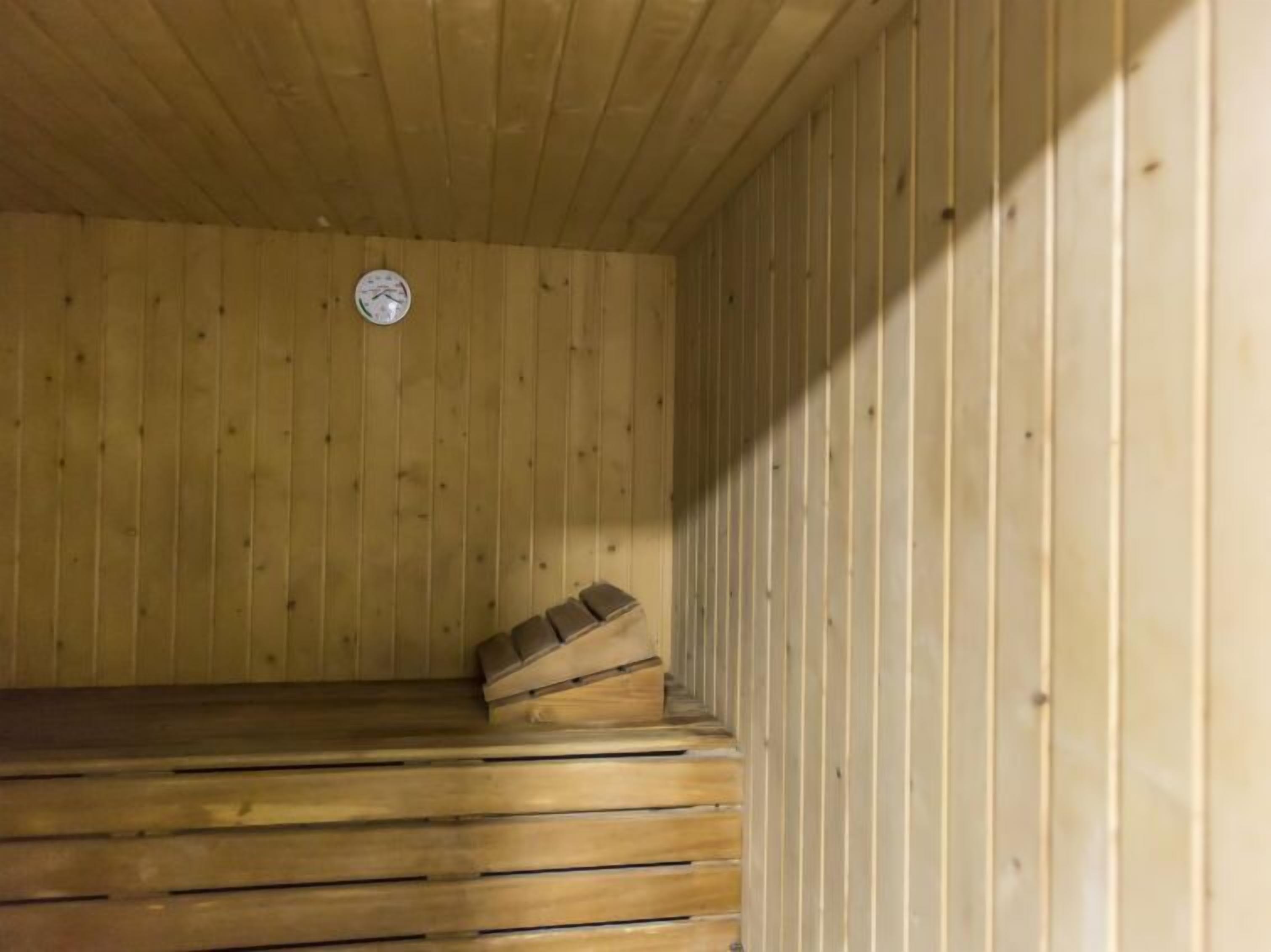 Ein Saunabereich mit Holzbänken und einer Uhr an der Wand.