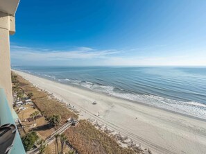 A beach with a clear view of the ocean, a sandy shore, and a few structures along the beach. - Oceanfront Luxe | Sand Dunes Eleven Twenty-Nine (Myrtle Beach)