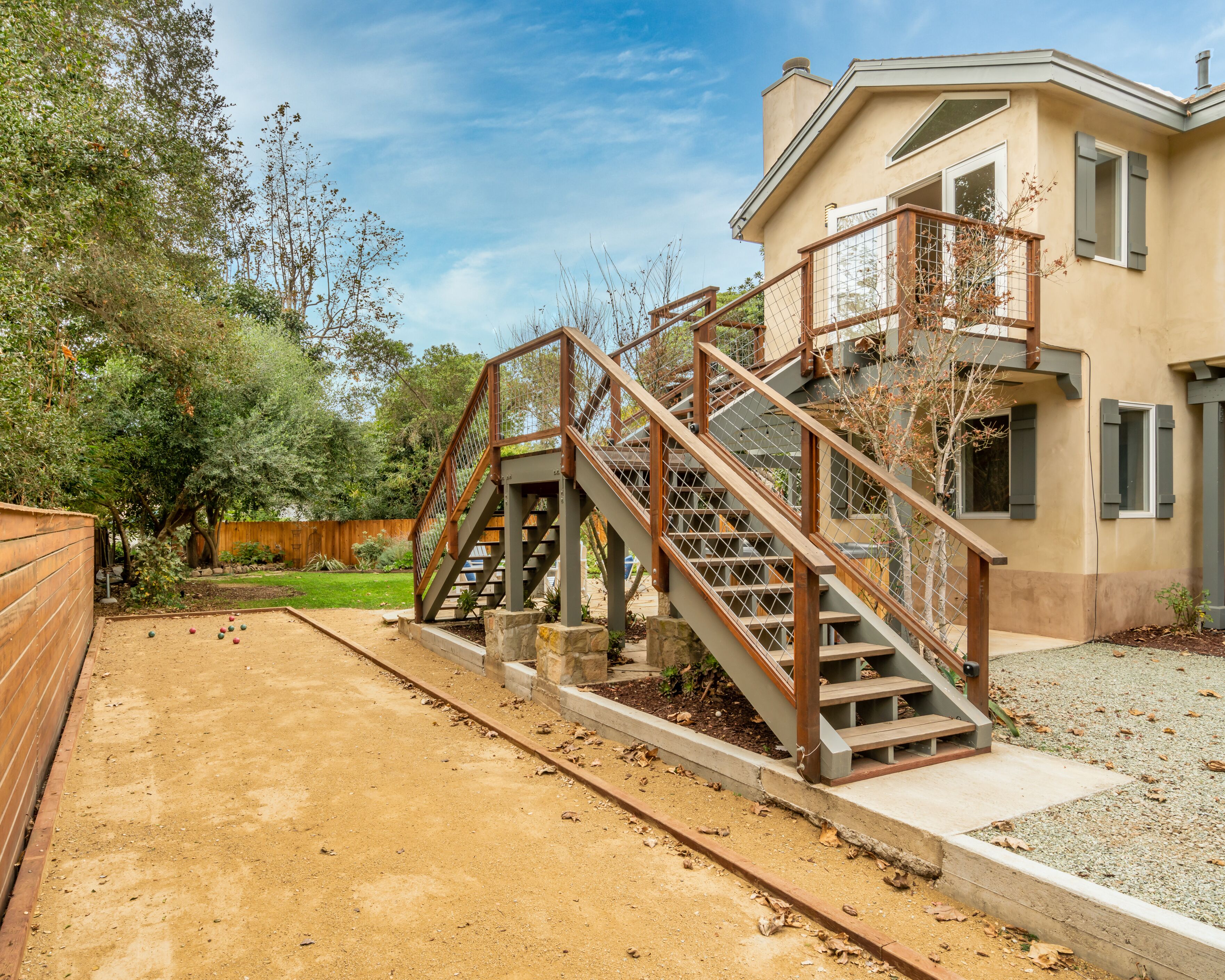 A two-story house with a wooden deck and a staircase leading to a balcony.