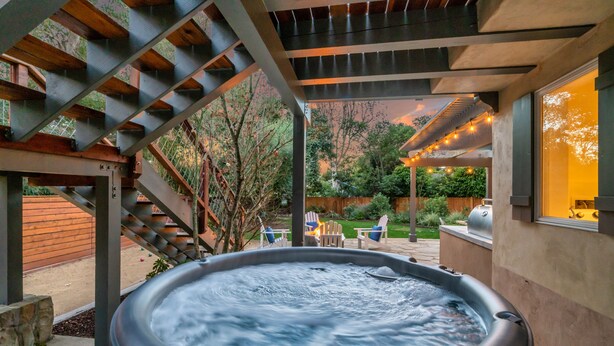 A hot tub under a wooden pergola with a view of a backyard patio area. - Secluded Luxury Haven | Hot Tub, Billiards, Firepit & Spa Ambiance near Beach (Montecito)