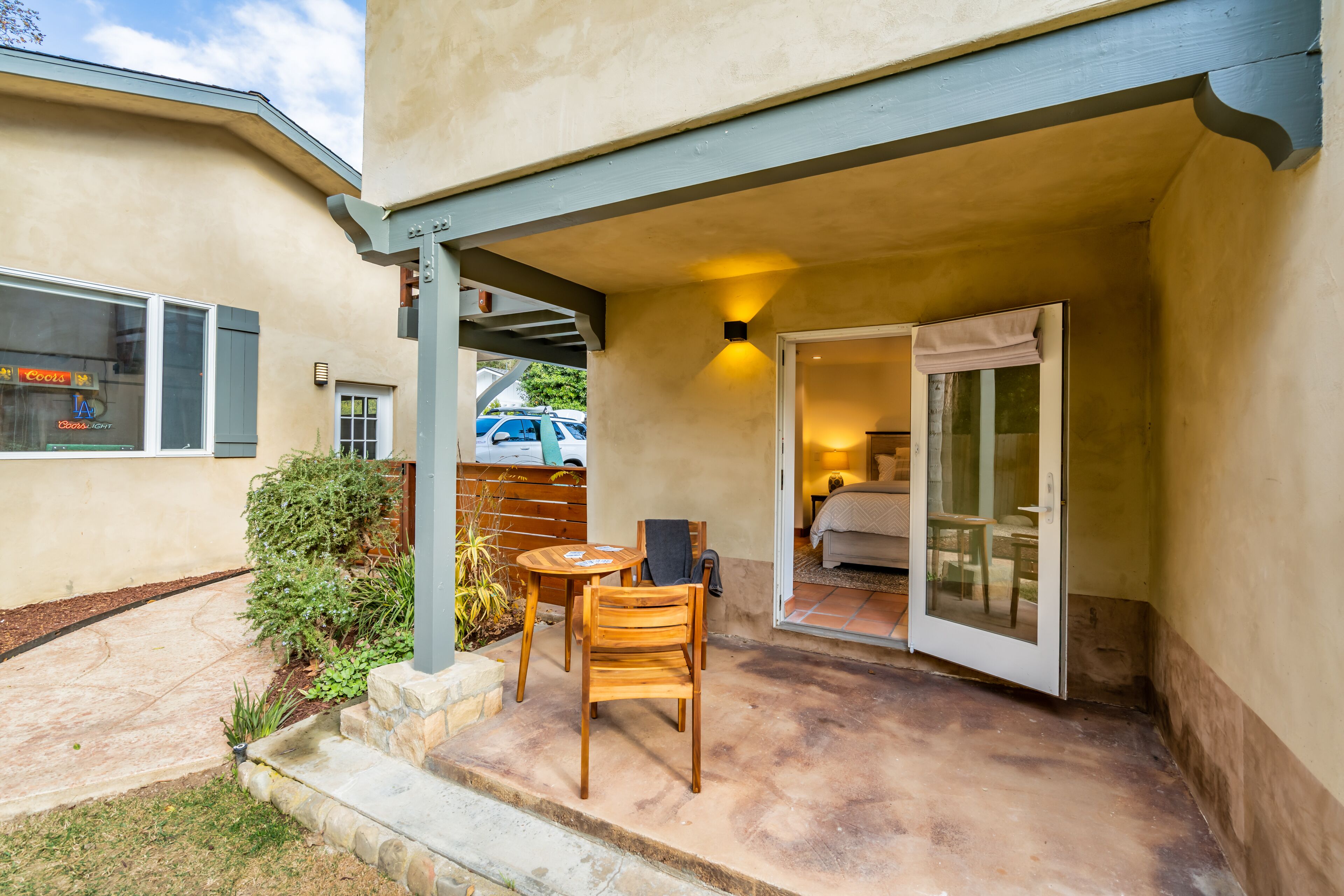 A patio with a table and chairs, a covered seating area, and a door leading to a bedroom.
