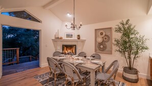 A dining room with a fireplace, dining table set for six, and a large potted plant. - Secluded Luxury Haven | Hot Tub, Billiards, Firepit & Spa Ambiance near Beach (Montecito)