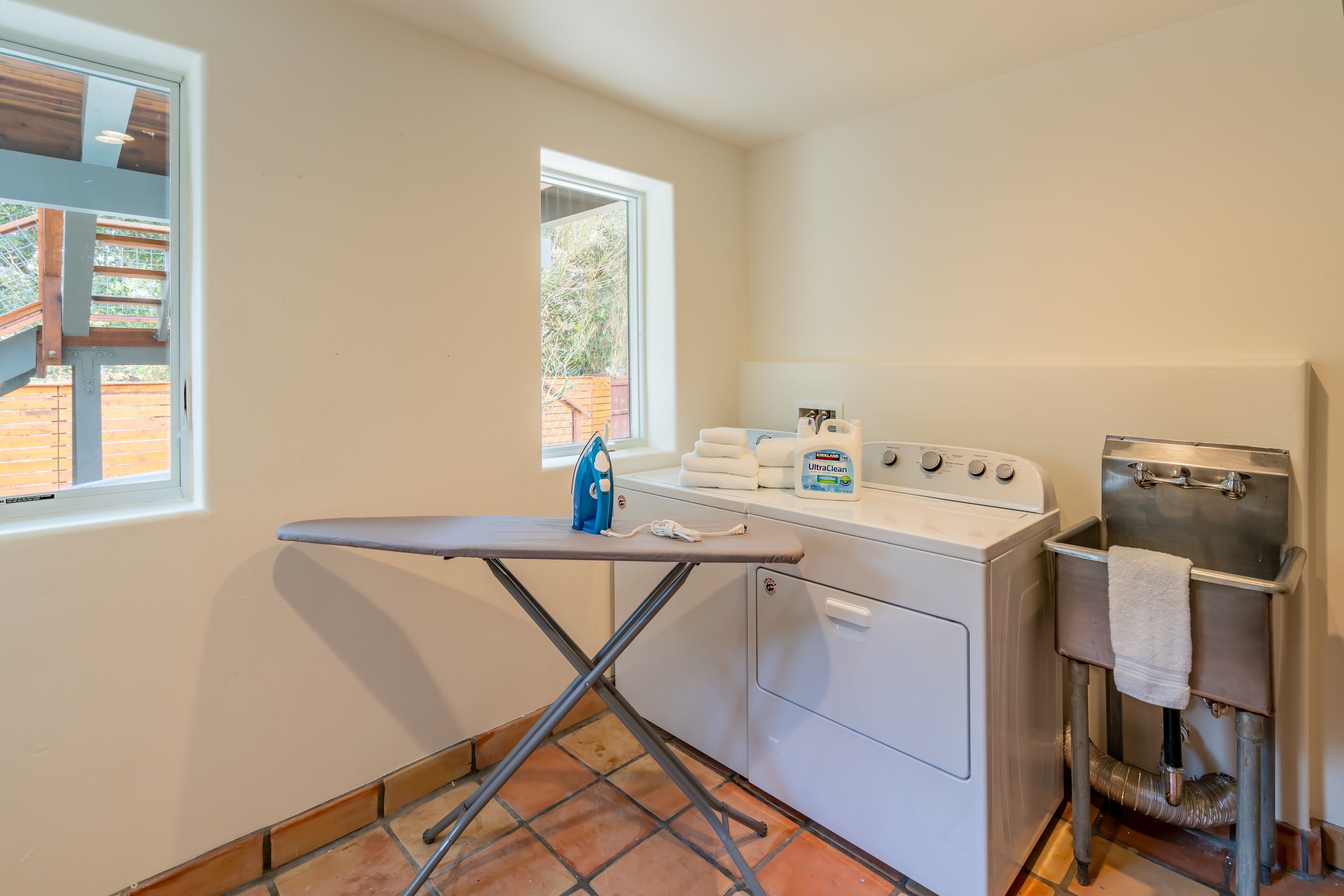 A laundry area with an ironing board, washing machine, and a sink.