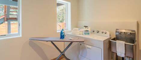 A laundry area with an ironing board, washing machine, and a sink.