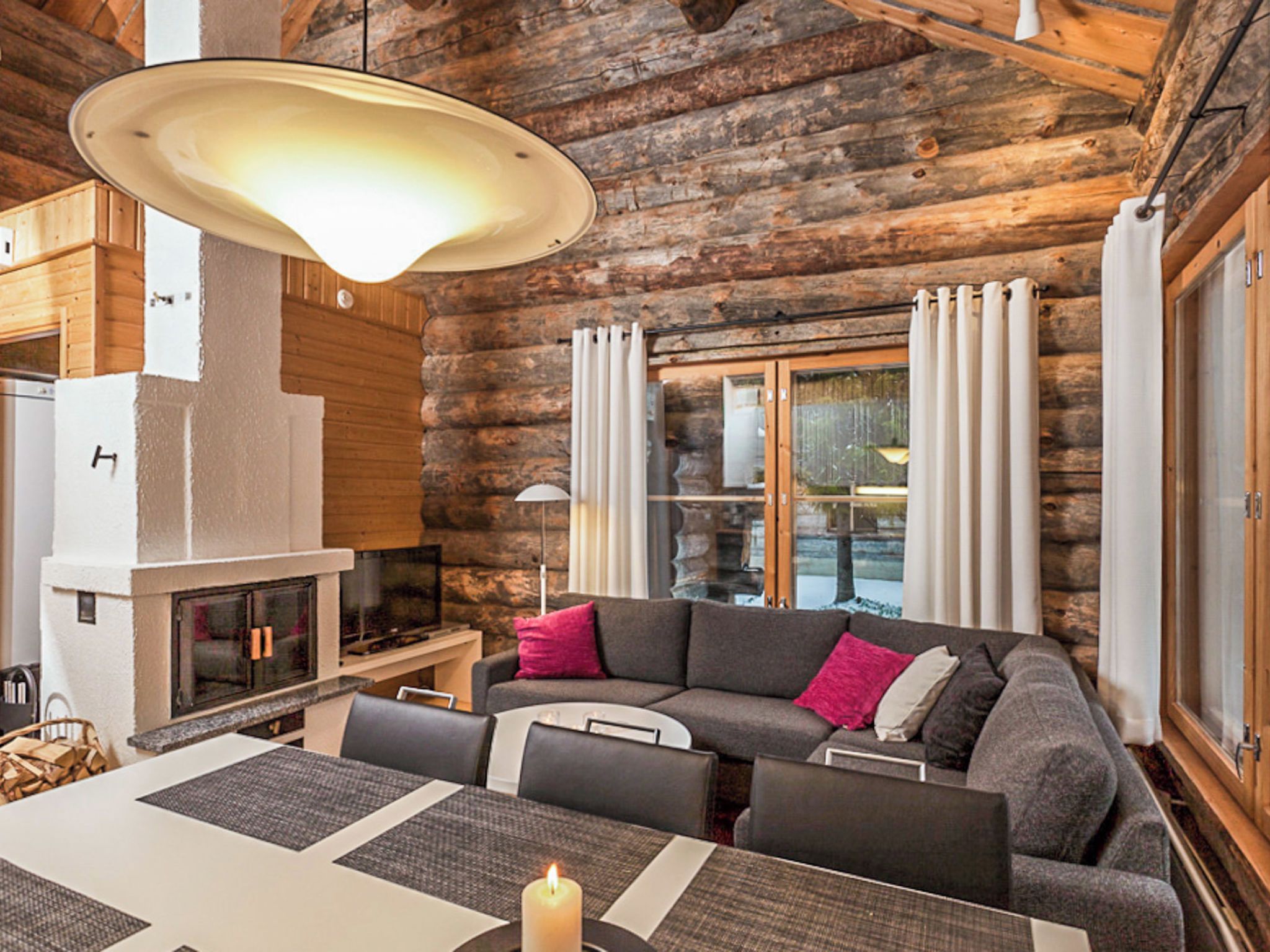 Ein gemütliches Blockhaus-Interieur mit Kamin, Essbereich und einer komfortablen Sitzecke.