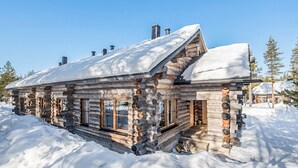Une cabane en rondins avec un toit enneigé, un revêtement extérieur en bois et de grandes fenêtres.