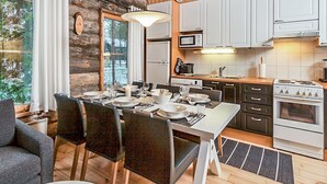 Une cuisine chaleureuse, aménagée dans le style d’un chalet, avec un coin repas, un plafond en bois et de grandes fenêtres.