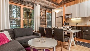 Un intérieur de chalet chaleureux comprenant un espace de vie, un coin repas et une cuisine.
