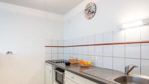 A compact kitchen with white cabinets, a black countertop, a stainless steel sink, and a microwave. - Le Hoche by Interhome (Quiberon)