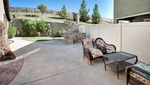 Un patio con una fogata de piedra, mobiliario de mimbre y vistas a un paisaje montañoso.