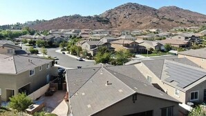Un barrio residencial con casas, una carretera serpenteante y una montaña al fondo.