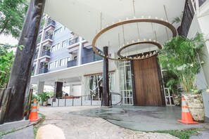 A modern building entrance with a circular light fixture, a staircase, and potted plants. - Ibooking Trams Square Chiang Mai (Chiang Mai)