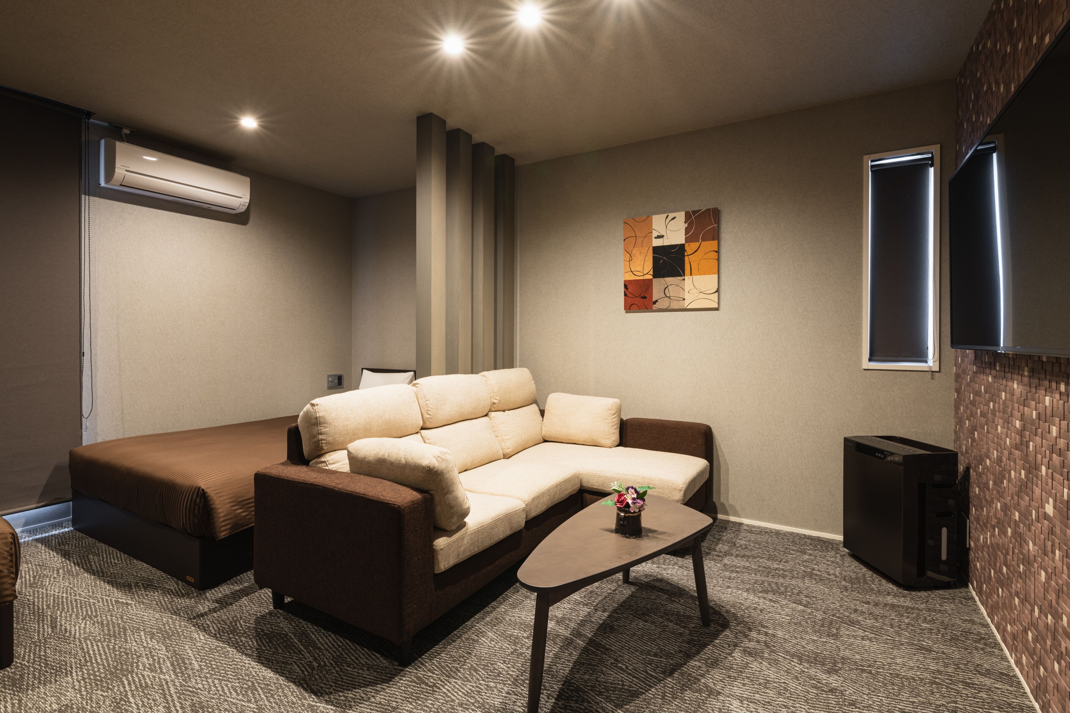 Ein modernes Wohnzimmer mit einer Eckcouch, einem Couchtisch und einem an der Wand befestigten Flachbildfernseher.