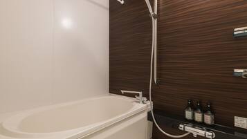 A modern bathroom with a bathtub, a shower, and a shelf with bottles.