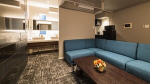 A modern living room with a blue sofa, a wooden coffee table, and a small decorative vase. - GRAND BASE Kagoshima Tenmonkan (Kagoshima)