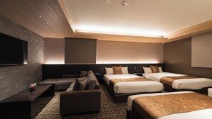 Ett hotellrum med en stor platt-TV, en soffa, två sängar med bruna sängkläder och en mönstrad matta.