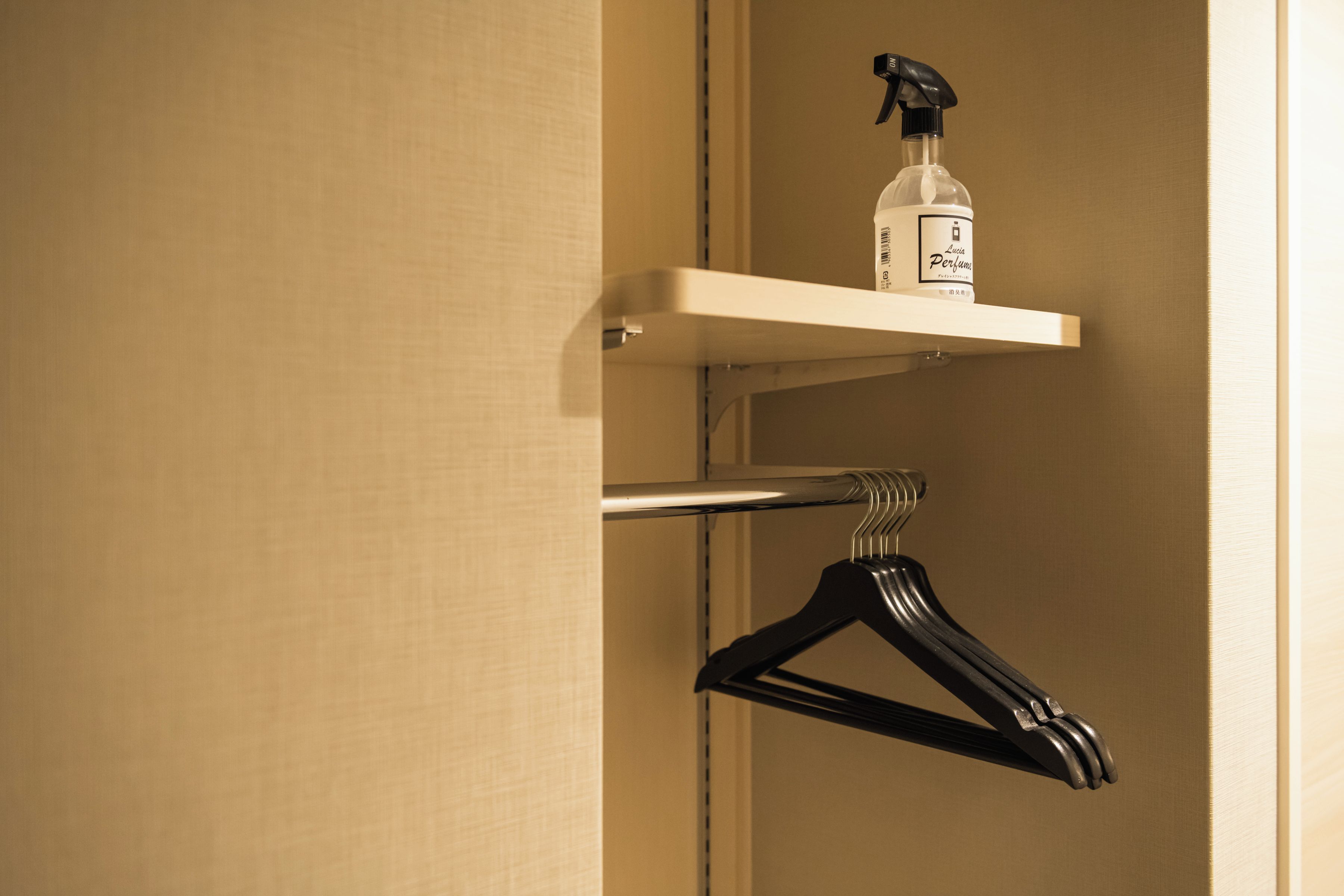 Ein Badezimmer mit einem Regal, auf dem sich eine Parfumflasche und ein schwarzer Kleiderbügel befinden.