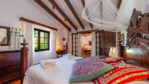 Une chambre à coucher avec un grand lit, une commode en bois, un miroir et une fenêtre avec des rideaux.
