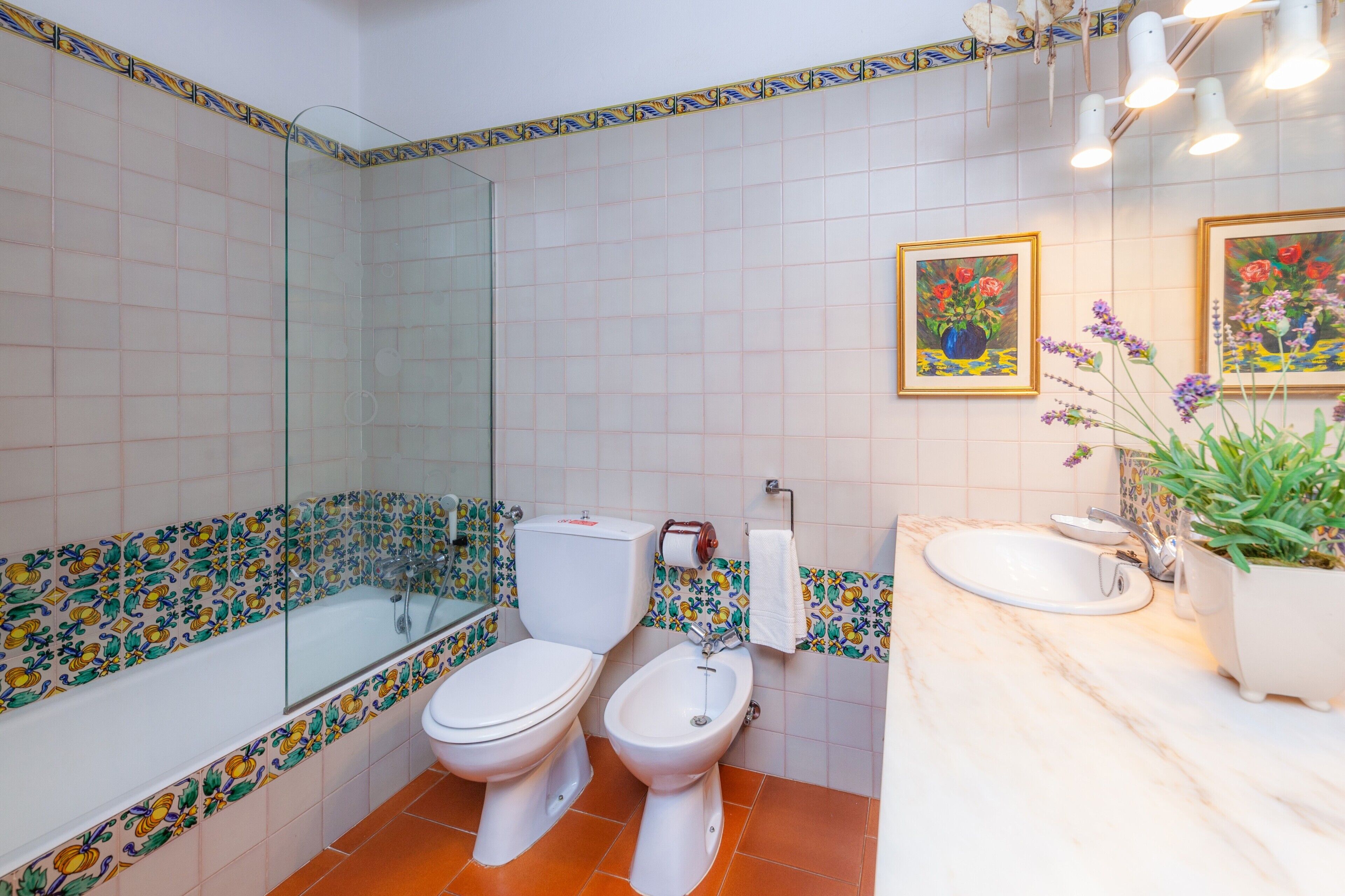 A bathroom with a glass-enclosed shower, two toilets, a bidet, a sink, and a mirror.