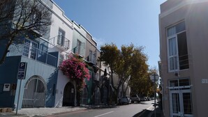 Une vue de rue avec des bâtiments, un panneau de signalisation indiquant un parking et un ciel dégagé.