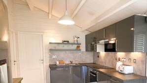 A modern kitchen with dark cabinets, a white countertop, and a hanging light fixture. - Secluded Countryside Lodge on 25 Acres | Private Deck & Views | Kent Escape (Biddenden)