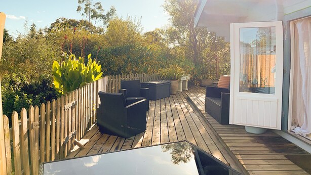 A wooden deck with outdoor furniture, a white door, and a view of trees and sky. - Secluded Countryside Lodge on 25 Acres | Private Deck & Views | Kent Escape (Biddenden)