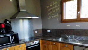 Una cocina con armarios de madera, una campana extractora de acero inoxidable, un microondas, un horno y un lavabo.