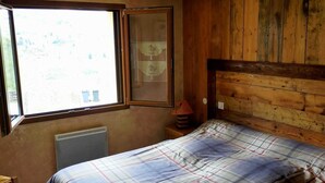 Un dormitorio con cama, ventana, radiador y paneles de madera.