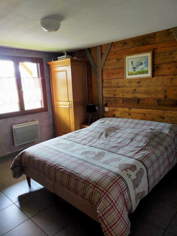 A bedroom with a bed, a wardrobe, a radiator, and a window with curtains.