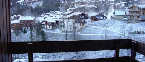 Une vue d’un village enneigé avec de nombreux bâtiments, dont un hôtel doté d’un balcon.
