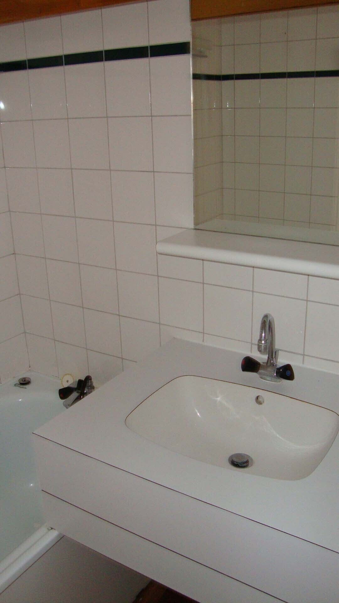 Une salle de bain avec un lavabo blanc, un miroir au-dessus et une baignoire.