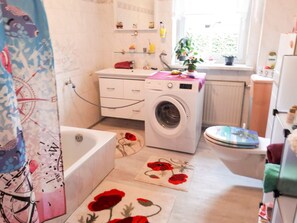 A compact bathroom with a washing machine, a bathtub, and a toilet. - Ferienzimmer Alt Sammit bei Krakow - Ferienzimmer (Krakow am See)
