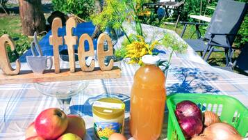 A table with a coffee sign, apples, eggs, a honey jar, and a green basket with onions.