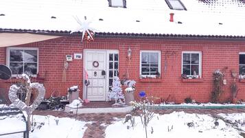 A red brick house with a white door, a wreath, and a Christmas tree.
