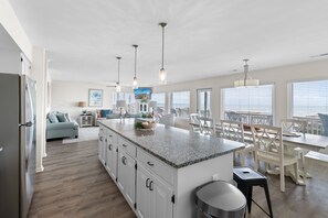 A modern kitchen with a large island, white cabinetry, and pendant lighting.