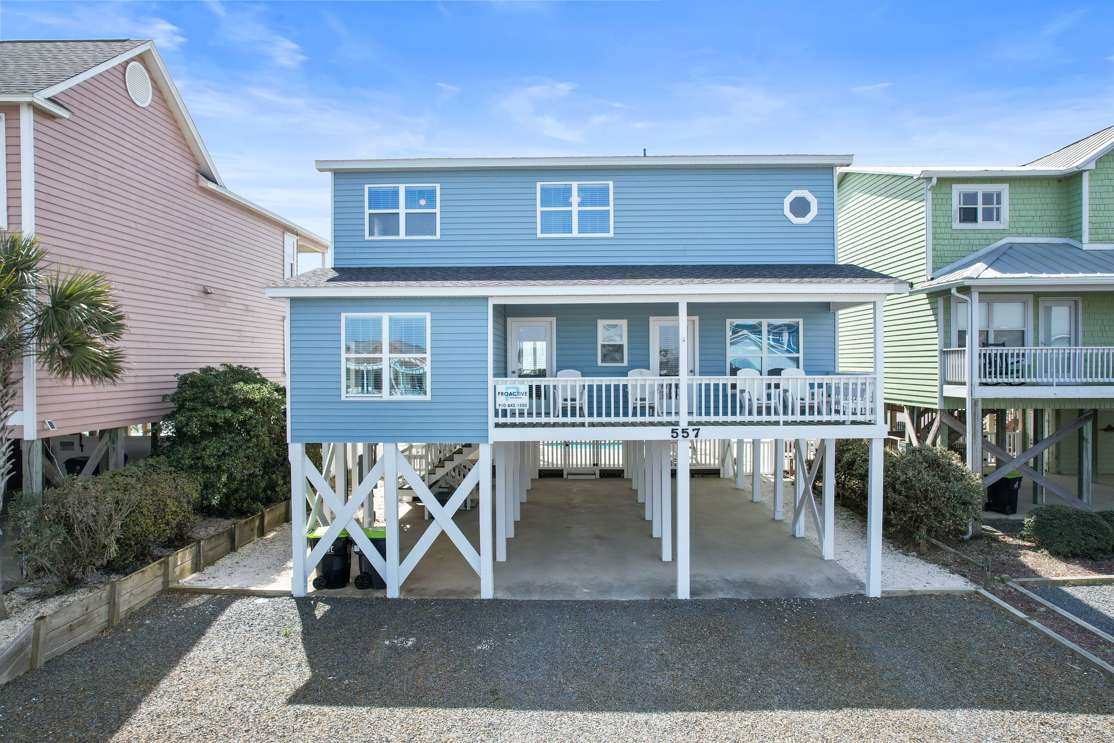 A two-story house with a porch, a number 557 sign, and a small garden area.