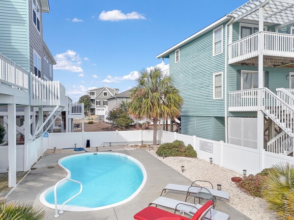 A residential area with a swimming pool, white fences, and houses with balconies. - "Holden Mystique" - 2nd Row Home w/ Pool, 4 Bedrooms / 3 Bathrooms (Holden Beach)