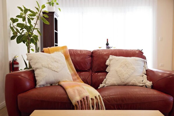 A brown leather sofa with two white pillows and a throw blanket.