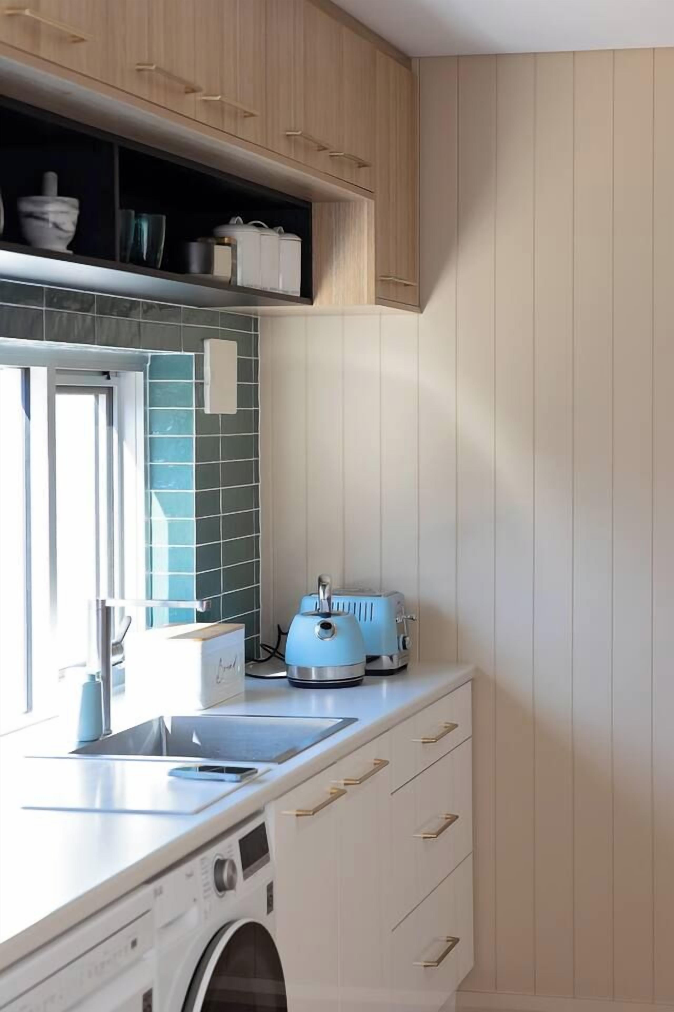 A compact kitchen with a washing machine, a toaster, and a window.