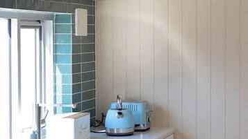 A compact kitchen with a washing machine, a toaster, and a window.