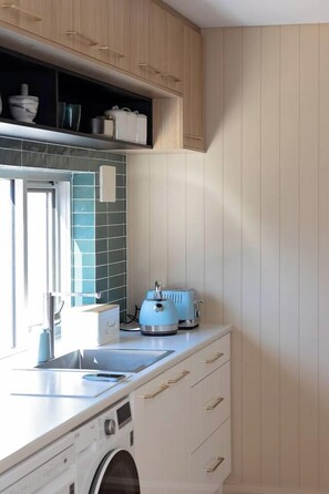 A compact kitchen with a washing machine, a toaster, and a window.