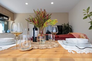 A dining table set with wine glasses, plates, and a vase with plants.
