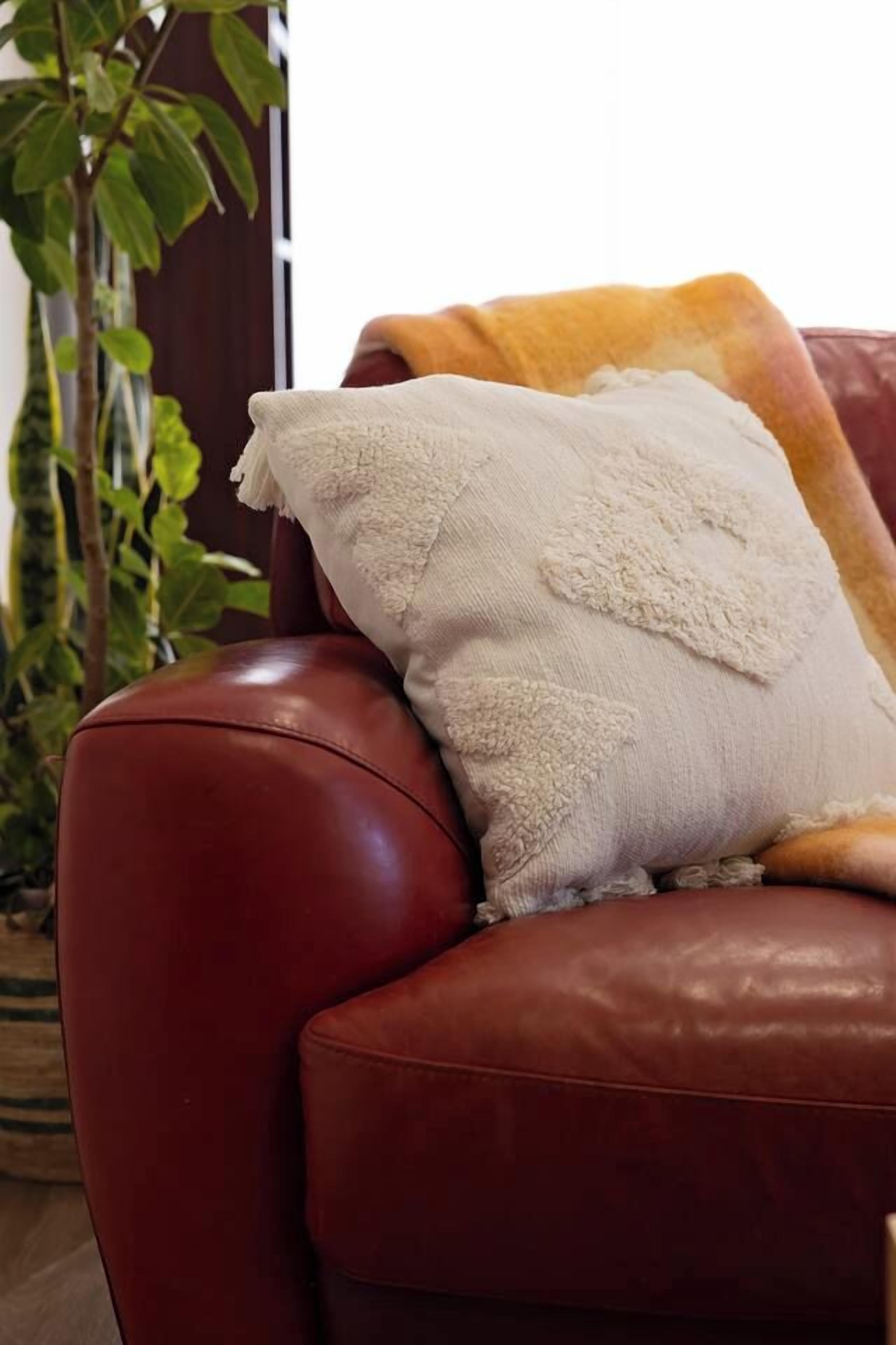 Un fauteuil en cuir marron avec un coussin blanc.