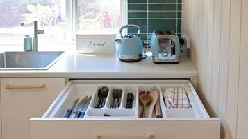 A kitchen with a drawer organizer containing utensils, a kettle, and a toaster on the countertop.