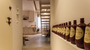 Un pasillo con una fila de botellas a la derecha y una escalera al fondo.