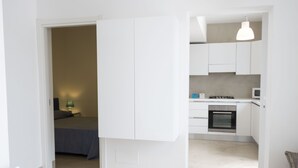 A modern kitchen with white cabinets, a gas stove, and a microwave. - Villa Azzurra (San Vito Lo Capo)